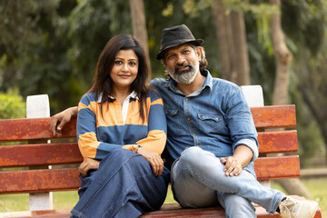 Indian overjoyed loving couple at park while looking at the camera. Romantic and Attractive couple in love, fun, hugging outside, spending leisure time together, relationship and people concept.