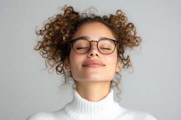 Obraz premium Young woman in a white sweater with curly hair enjoys a moment of calm in a minimalistic indoor space