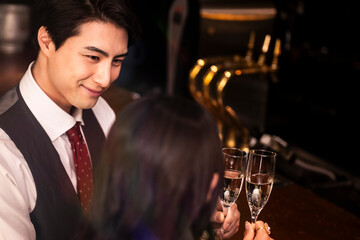 Stylish man in formal attire looking at his partner while toasting champagne in a moody upscale bar. The scene captures romantic eye contact and elegant intimacy.