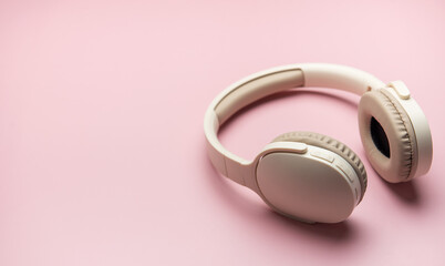 Modern wireless headphones lying on pink background
