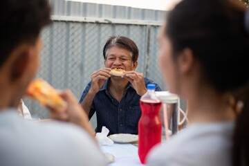 Asian man is happily eating pizza.