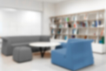 Blurred view of modern living room with sofa and soft bench. room interior with couch, armchair and coffee table or shelving units. stylish living room. comfortable workplace near big window.