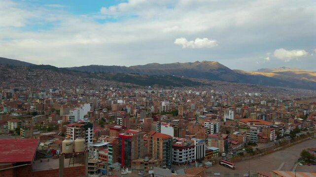 Expansive daytime view of Cusco city from Puerta del Sol and Mirador Pachacutec in the Wanchaq neighborhood, showing dense urban layout with Andean mountains in the background.