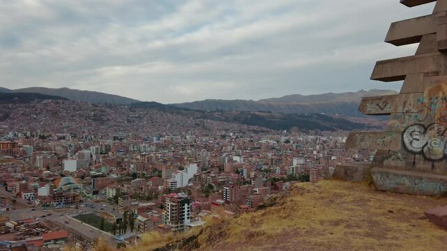 Panoramic leftward shot overlooking Cusco city reveals Puerta del Sol Mirador, Mirador Cusco - Panorama del Inca, and Mirador Pachacutec under a cloudy sky at sunrise.