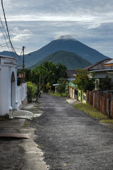 A narrow path down the street in the village of Ternate island with a view of a volcano on adjacent Tidore island in North Maluku province