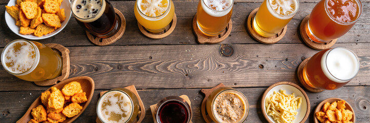 Variety of craft beers with snacks on rustic wooden table top view
