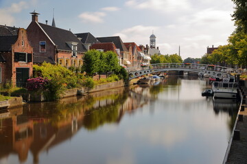 Reflections of traditional houses, barges and boats on the little canal (klein Diep) in Dokkum, Friesland, Netherlands, with the Oud Stadhuis (Old Town Hall, built in 1610) in the background