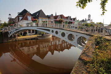 Reflections of traditional houses and a footbridge (Turfmarkt) on the little canal (klein Diep) in Dokkum, Friesland, Netherlands, with the Oud Stadhuis (Old Town Hall, built in 1610) in background