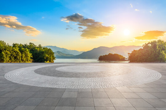 Empty square floor and lake with mountain scenery at sunset