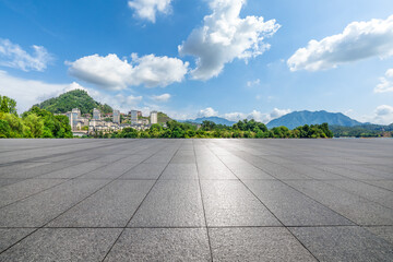 Empty square floor with distant mountain and the town under blue sky