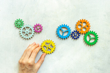 Hand is putting together cogwheels. Business automation and corporate work concept