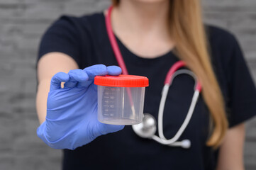 Doktorka trzyma pusty plastikowy pojemnik na próbkę do analizy w laboratorium