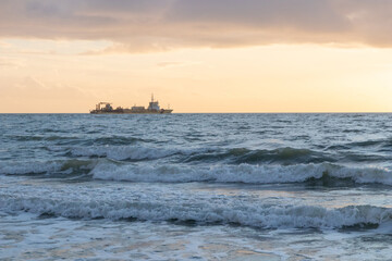 Sunset sky over the English Channel with a silhouette of a cargo ship at horizon, La-Manche, France