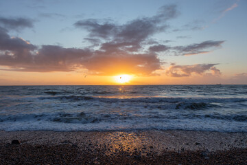 Colorful sunset over the English Channel. Beauty of the sea and ocean, pebbles beach of Normandy,...