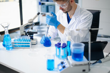 male scientist working with micro pipettes analyzing biochemical samples, advanced science chemical...