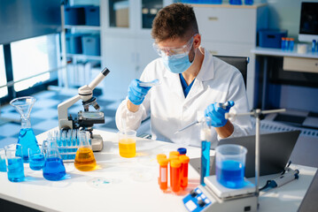 male scientist working with micro pipettes analyzing biochemical samples, advanced science chemical...