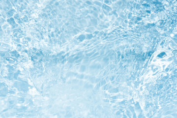 Blue water with ripples on the surface. Defocus blurred transparent blue colored clear calm water surface texture with splashes and bubbles. Water waves with shining pattern texture background.