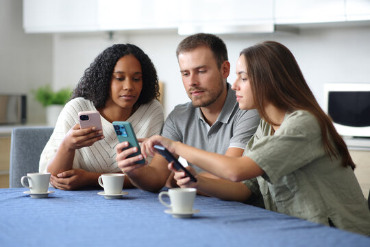 Three roommates checking phones in the kitchen