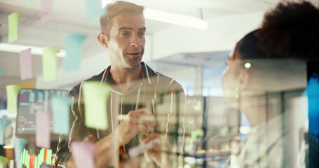 Man, woman and notes on glass wall at office, discussion and planning with problem solving at startup. Business people, team and talk by window with synergy, solution and project at creative agency