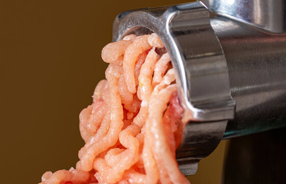 Process of transformation meat into forcemeat. Close up of front part of meat grinder or mincing-machine with ground beef exiting therefrom. Raw, ground
