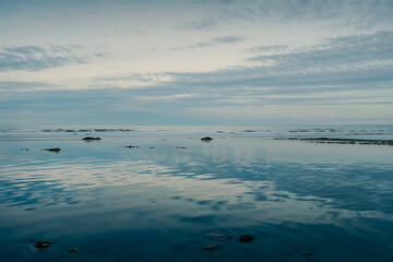 Tranquil ocean view with rocks under a clear blue sky at dusk