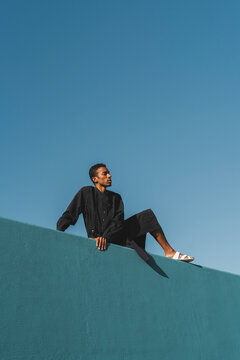 Young man wearing black kaftan on blue wall