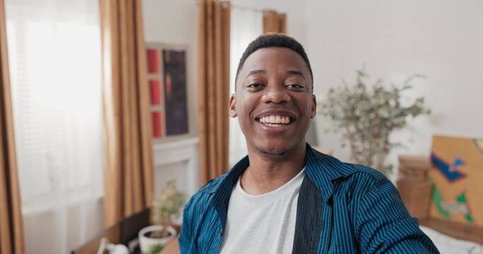 A smiling guy records a vlog in his new apartment. Surrounded by cardboard boxes, he talks to his family through the camera and shares his first impressions of the move.