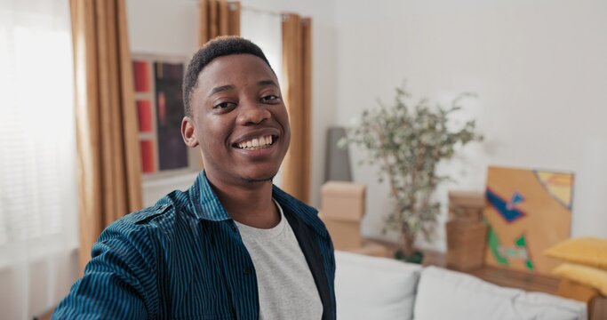 In a freshly bought house, a young man records a message for his loved ones. He looks into the camera, speaks with excitement, and points to boxes in the background.