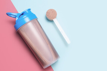 Bottle with cocktail and scoop with protein powder on blue and burgundy background close-up top...