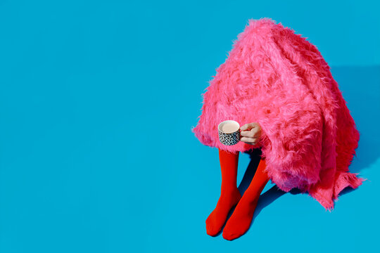 Man covered with pink blanket holding coffee cup in the morning