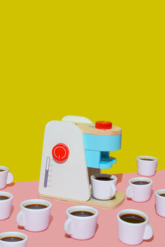 Toy coffee maker with cups on a pink background and yellow backdrop