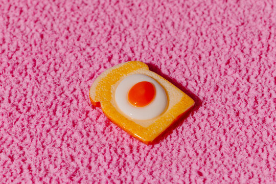 Toy toast with fried egg on a pink carpet indoors