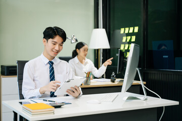 Young businessman working at office with laptop, tablet and taking notes on the paper..