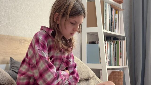 Young girl feeling stomach ache while sitting on bed