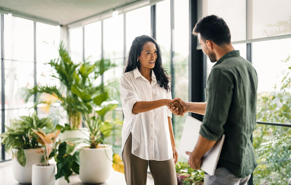 Two happy diverse multiethnic business team people working, talking in corporate office