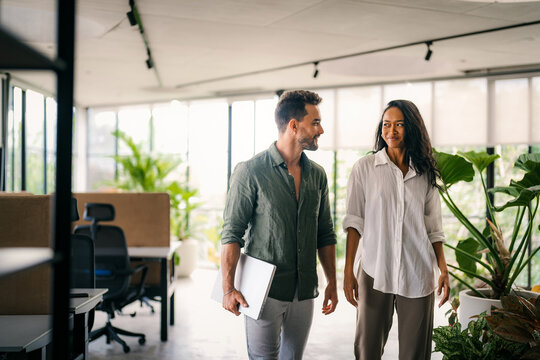 Two happy diverse multiethnic business team people working, talking in corporate office