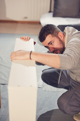 Obraz premium Man working and assembling furniture in a new apartment.