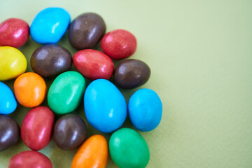Colorful chocolate candies on green background. Selective focus.