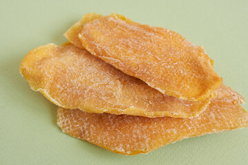 Dried mango slices on green background, close-up, horizontal