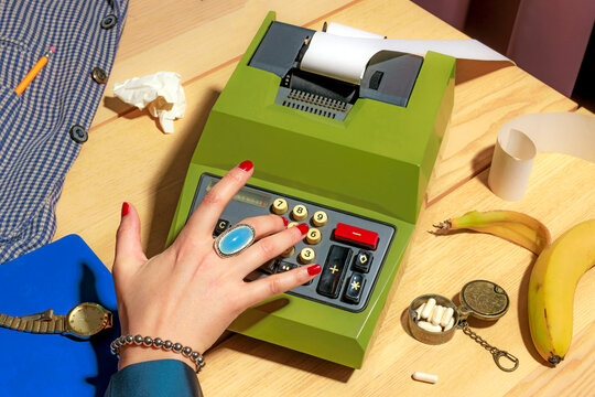 Hand using a vintage 60s calculator on a desk with office supplies