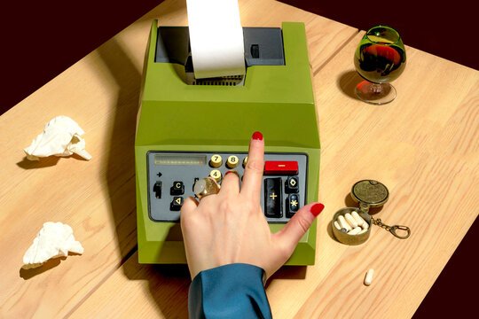 Closeup of a hand using a vintage calculator on a desk with pills and a glass