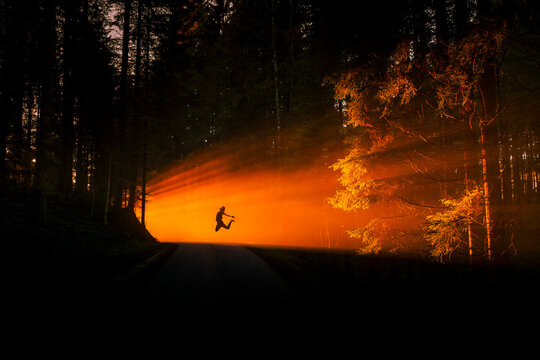 Silhouette of a woman jumping in a misty forest at sunset