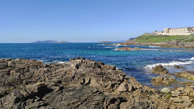 A stunning coastal video showing the vast ocean, the beautiful Islas C&iacute;es in the distance, and the historic Parador de Baiona, all under a bright and clear Galician sky.