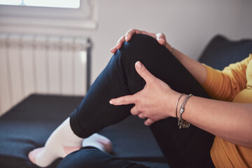 Woman with painful knee and leg injury at home.