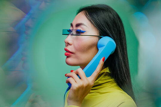 Stylish woman with glasses holding a retro blue phone