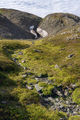 Rocky slope of a fell and lingering snow in Varanger Peninsula on a beautiful summer day