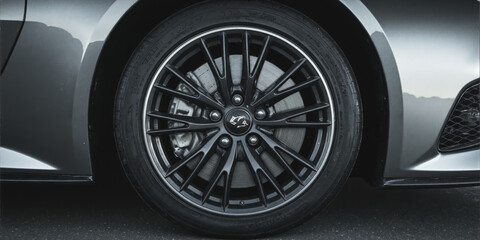 A close-up of a car's alloy wheel with intricate spoke design, highlighting craftsmanship and performance, set against a blurred background to emphasize