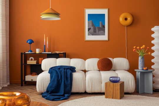 Modern cozy living room with white boucle sofa, orange wall and eclectic decor in bold colors...