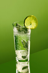 Sparkling mojito cocktail with mint leaves and lime slice against green background. Concept of party, freshness, alcohol, vacation, joy, nightlife, fun, mix, tropical taste, celebration.