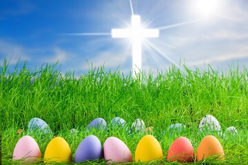 Colorful easter eggs on green grass and bright cross